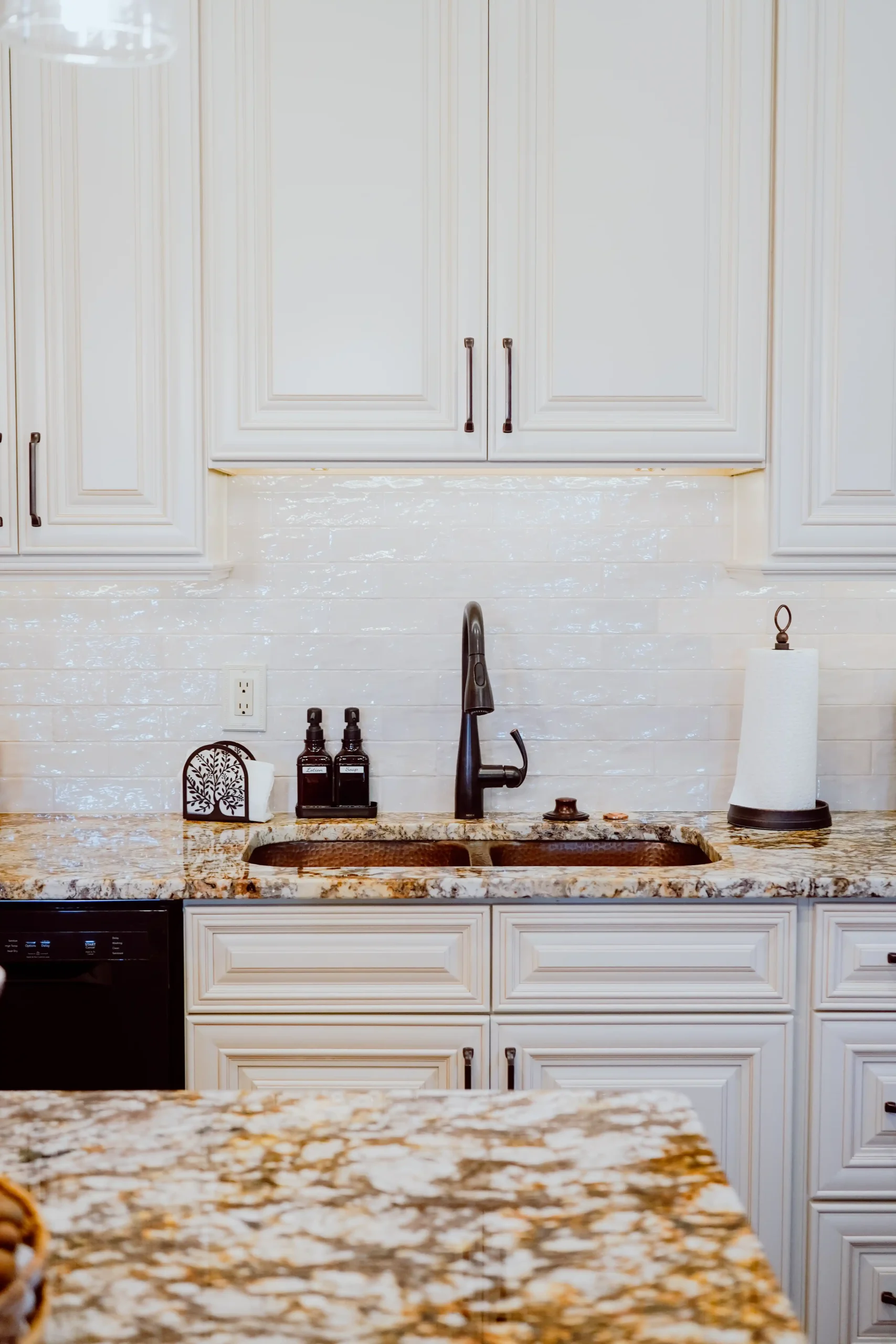 Kitchen sink area with a black faucet, granite countertop, and white cabinets in an in-law suite